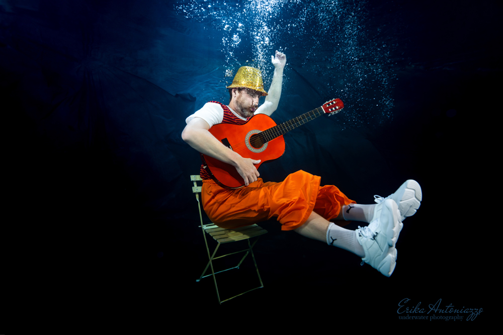Onderwaterfoto model man in oranje kleding met gitaar