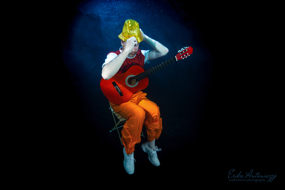 Onderwaterfoto model man in oranje kleding met gitaar