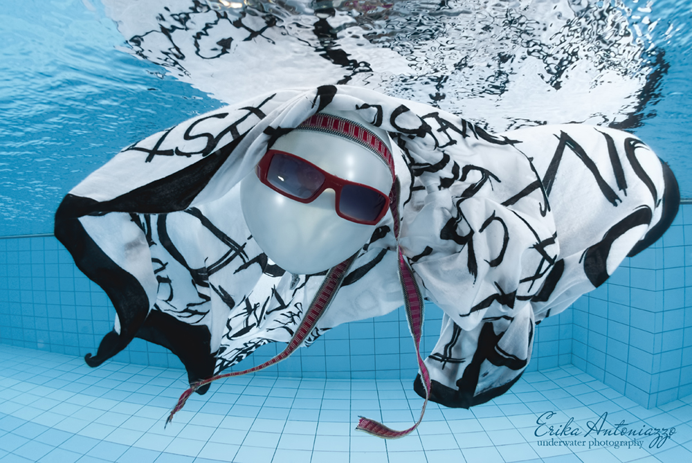 Witte ballon met zonnebril, bandanna en zwart-witte doek onder water in het zwembad