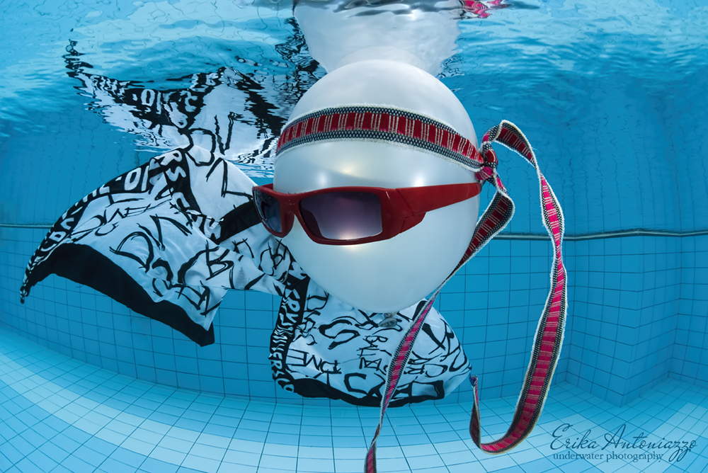 Witte ballon met zonnebril, bandanna en zwart-witte doek onder water in het zwembad