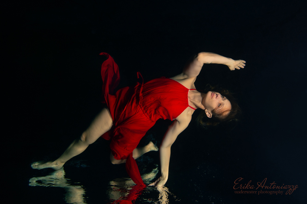 Onderwaterfoto model vrouw in rode jurk, met weerspiegeling